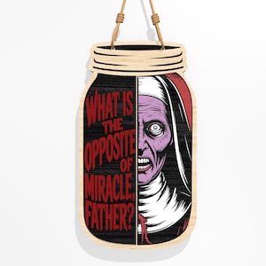 Puede incluir: Cartel de madera con forma de tarro con un gr&aacute;fico de monja espeluznante. La cara de la monja es morada y blanca, con una expresi&oacute;n amenazante. El texto rojo dice "WHAT IS THE OPPOSITE OF MIRACLE, FATHER?" Se adjunta una cuerda de yute para colgar.