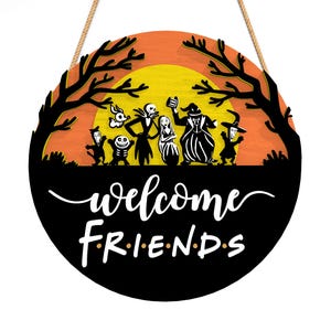 Pu&ograve; includere: Cartello rotondo in legno di Halloween con una silhouette nera di alberi e personaggi di Nightmare Before Christmas contro un tramonto arancione e giallo. Le parole "welcome friends" sono scritte in bianco.