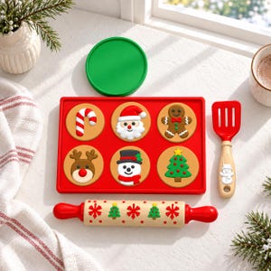 May include: A red rectangular silicone baking mould with six circular cavities featuring embossed designs of a candy cane, Santa Claus, gingerbread man, reindeer, snowman, and Christmas tree. Includes a matching green lid, a red and beige rolling pin with festive patterns, and a red spatula with a snowman handle.
