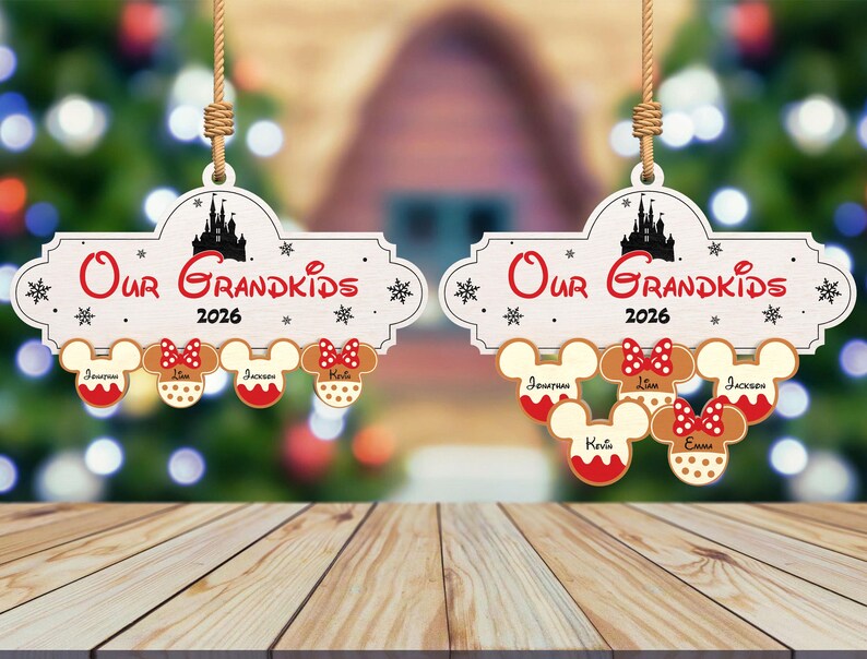 May include: Wooden Christmas ornament with the text "Our Grandkids 2026" and a silhouette of a castle. Below are gingerbread Mickey Mouse heads with names. The ornament hangs from a jute string.