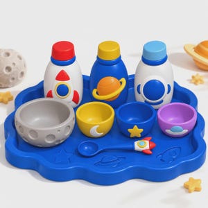 May include: A blue cloud-shaped tray holding three bottles with space-themed designs, three small bowls with moon, star, and UFO motifs, a grey cratered bowl, and a spoon with a rocket ship handle. The set features vibrant colours and space icons.