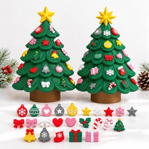 May include: Two green Christmas tree figures with brown bases and yellow star toppers, decorated with various colorful ornaments. Below the trees are loose, small, flat decorative charms shaped like hearts, bells, bows, gifts, and snowflakes.