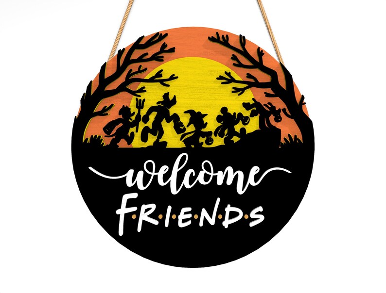 Pu&ograve; includere: Cartello rotondo in legno di Halloween con una silhouette nera di personaggi dei cartoni animati in costume contro un tramonto arancione e giallo. Le parole "welcome friends" sono scritte in bianco. Appeso con una corda naturale.