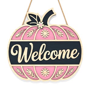 May include: A wooden pumpkin-shaped welcome sign with a pink interior and a black banner that reads "Welcome". The sign has a natural wood border and is decorated with floral and leaf cutouts. It hangs from a natural fiber rope.