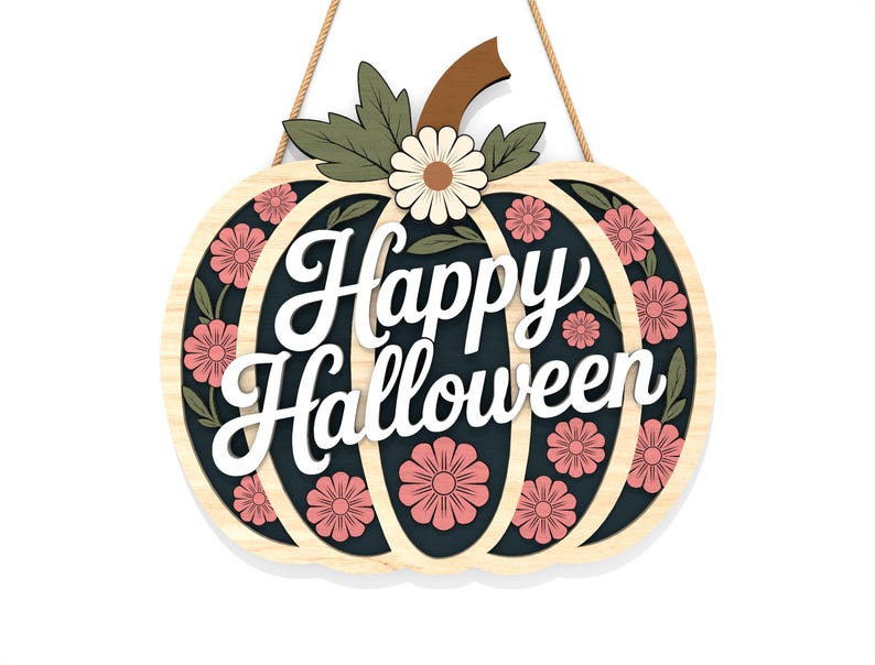 May include: A wooden pumpkin-shaped sign with the words "Happy Halloween" in white script. The sign features pink flowers and green leaves on a dark background, with a light wood border. A brown stem and a daisy are at the top, with a jute rope for hanging.