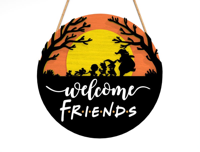 Pu&ograve; includere: Cartello di benvenuto rotondo in legno a tema Halloween. Il cartello presenta sagome nere di personaggi e alberi su uno sfondo arancione e giallo. Le parole "welcome FRIENDS" sono scritte in bianco.