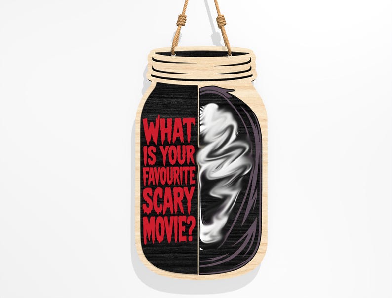 Puede incluir: Letrero de madera con forma de tarro, con la pregunta "WHAT IS YOUR FAVOURITE SCARY MOVIE?" en rojo. El lado izquierdo es negro, el lado derecho presenta una imagen fantasmal blanca. Se adjunta una cuerda de yute para colgarlo.