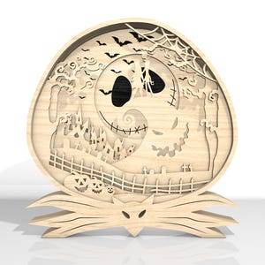 K&ouml;nnte beinhalten: Holzdekoration zum Thema Halloween mit einem mehrschichtigen Design. Das Design umfasst ein l&auml;chelndes Gesicht, Flederm&auml;use, ein Spukhaus und K&uuml;rbisse. Die Dekoration wird von einem stilisierten Sockel getragen, wodurch ein dreidimensionaler Effekt entsteht.
