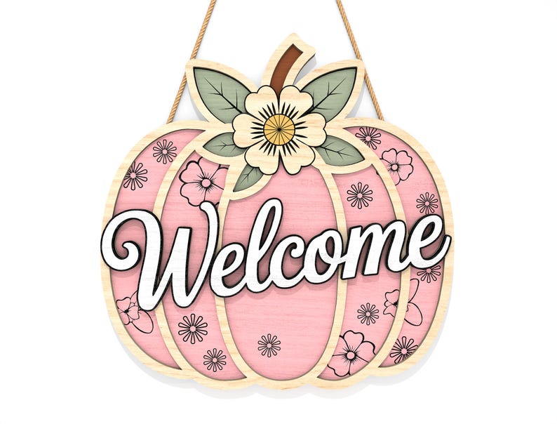 May include: A wooden pumpkin-shaped welcome sign with a pink center and floral accents. The word "Welcome" is written in white script across the front. The sign is decorated with a flower and leaves at the top and is suspended by a natural rope.