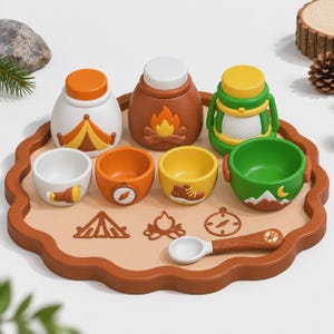 Puede incluir: Un juego de juguetes con temática de acampada que incluye una bandeja redonda con iconos de tienda, hoguera y brújula. El set contiene tres recipientes con tapa, cuatro cuencos pequeños con motivos de exterior y una cuchara.