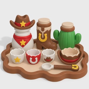 Può includere: Un set di giocattoli a tema western su un vassoio marrone, composto da un pupazzo di neve bianco con cappello da cowboy marrone, uno stivale da cowboy marrone, un cactus verde, tre piccole tazze smerlate e un cucchiaio marrone.