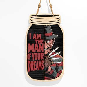 Puede incluir: Cartel de madera con forma de tarro que presenta un personaje de pel&iacute;cula de terror con sombrero y guante con cuchillas. El cartel tiene el texto "I AM THE MAN OF YOUR DREAMS" en rojo. El cartel es de madera y tiene una cuerda para colgar.