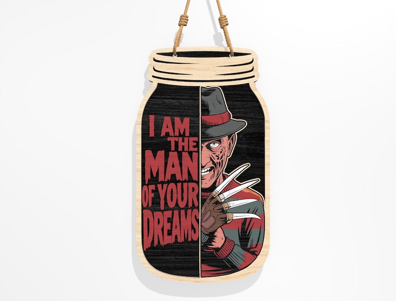 Puede incluir: Cartel de madera con forma de tarro que presenta un personaje de pel&iacute;cula de terror con sombrero y guante con cuchillas. El cartel tiene el texto "I AM THE MAN OF YOUR DREAMS" en rojo. El cartel es de madera y tiene una cuerda para colgar.