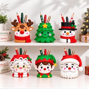 Puede incluir: Un conjunto de seis portalápices decorativos con personajes navideños que incluyen un reno, un árbol de Navidad, un muñeco de nieve, una figura de la Señora Claus, un elfo y Santa Claus, con detalles coloridos y varios lápices.