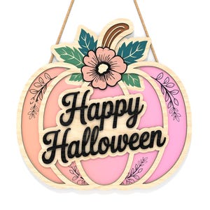 May include: A wooden pumpkin-shaped sign with the words "Happy Halloween" in black script. The sign features a pink and orange gradient, floral accents, and a decorative flower. It hangs from a natural rope.