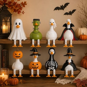 May include: A set of eight Halloween-themed duck figurines sitting on a shelf. The ducks are dressed as a ghost, Frankenstein's monster, a mummy, a vampire, a pumpkin, a witch with a pumpkin body, a skeleton, and a witch with a black cape.