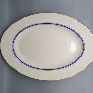 May include: White oval serving platter with a blue and gold trim.