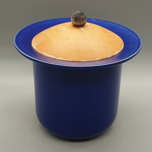 Puede incluir: Un tarro de cerámica azul con tapa de madera. La tapa tiene un pequeño pomo en la parte superior.