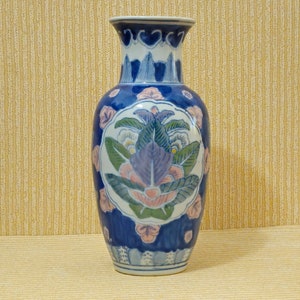 Peut inclure: Un vase en céramique bleu et blanc avec un motif floral. Le vase a une large ouverture et un col étroit. Le motif floral est dans des tons de rose, bleu et vert.