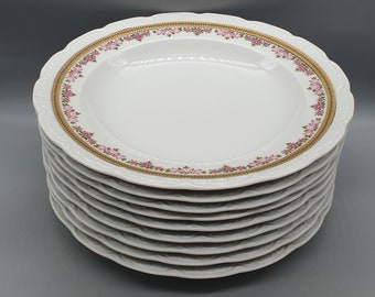 Könnte beinhalten: Ein Stapel von zehn weißen Porzellantellern mit einem goldenen und rosafarbenen Blumendesign am Rand.