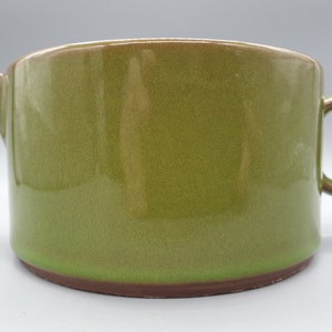 Könnte beinhalten: Ein grüner Keramik-Krug mit braunem Rand und Henkel. Der Krug ist glasiert und hat eine glatte Oberfläche.