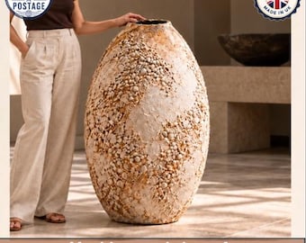 May include: A large, oval-shaped floor vase with a textured, off-white and tan surface covered in small, pebble-like protrusions. The text at the bottom reads: Machine-made is perfect. Handmade is unique.