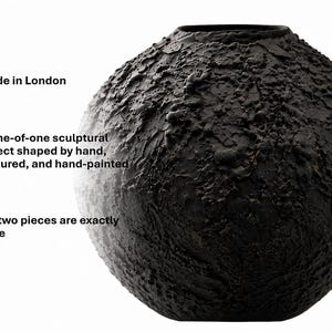 Op de afbeelding: Een bolvormige zwarte vaas met een sterk getextureerd, kraterachtig oppervlak. De tekst links luidt: Made in London, A one-of-one sculptural object shaped by hand, textured, and hand-painted, No two pieces are exactly alike.