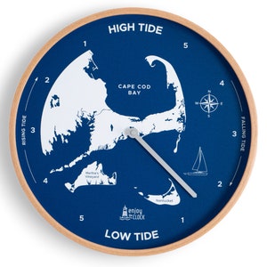 Op de afbeelding: Een blauwe en witte nautische klok met een kaart van Cape Cod Bay. De wijzerplaat van de klok heeft de woorden "High Tide" en "Low Tide" en een kompasroos. De wijzers van de klok zijn zilverkleurig.