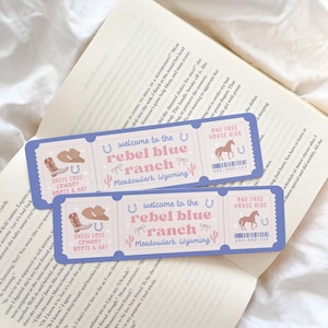 Puede incluir: Dos marcapáginas azules claros con forma de billete con el texto "welcome to the rebel blue ranch Meadowlark, Wyoming". Cada marcapáginas presenta un sombrero de vaquero, botas y una ilustración de caballo.