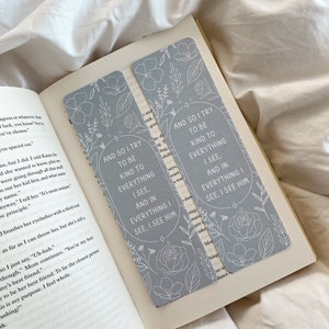 Puede incluir: Dos marcap&aacute;ginas gris claro con dise&ntilde;os florales y el texto "AND SO I TRY TO BE KIND TO EVERYTHING I SEE, AND IN EVERYTHING I SEE, I SEE HIM." Los marcap&aacute;ginas est&aacute;n en un libro abierto.