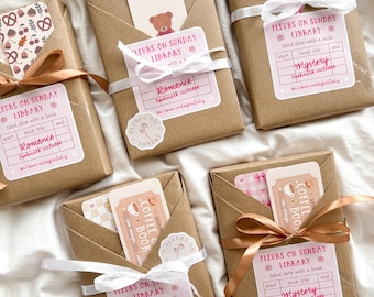 May include: Several wrapped books with tags that read "Fleurs on Sunday Library." Each book is wrapped in brown paper and tied with ribbon. The tags include the words "Romance" and "Mystery" and include a bookmark.