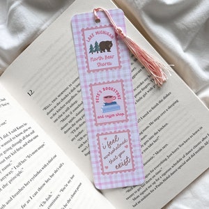 May include: A pink and white plaid bookmark with three rectangular designs. The top design says "Lake Michigan North Bear Shores" with a bear and trees. The middle design says "Pete's Bookstore and coffee shop". The bottom design says "I feel overwhelmed that you exist".