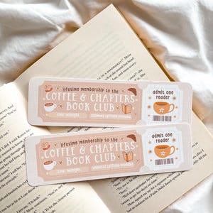 May include: Two rectangular bookmarks with a light peach background and the text "Coffee & Chapters Book Club". Each bookmark features a coffee cup and book illustration. One says "Admit one reader".