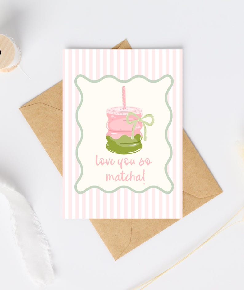 May include: A greeting card with a pink and white striped background. The card features a matcha drink illustration with the text "love you so matcha!". The card is inside a brown envelope.