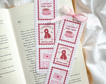 May include: Bookmarks with a pink and white gingham pattern, featuring postage stamp designs with phrases like "I watched it begin again" and "I remember it all too well." A pink ribbon is attached to the bookmarks, which are placed on an open book.