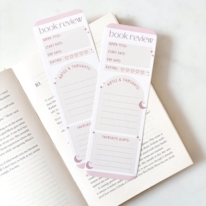 Op de afbeelding: Twee roze en witte boekenleggers voor boekrecensies met de tekst "book review", "Book Title", "Start Date", "End Date", "Rating", "Notes & Thoughts" en "Favorite Quote". De boekenleggers liggen op een open boek.