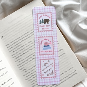 May include: A pink and white plaid bookmark with three rectangular designs. The top design says "Lake Michigan North Bear Shores" with a bear and trees. The middle design says "Pete's Bookstore and coffee shop". The bottom design says "I feel overwhelmed that you exist".