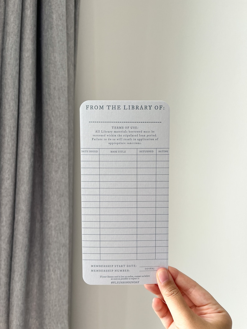 K&ouml;nnte beinhalten: Eine rechteckige Bibliothekskarte mit abgerundeten Ecken, vor wei&szlig;em Hintergrund gehalten. Die Karte tr&auml;gt den Text "FROM THE LIBRARY OF:" und einen Abschnitt f&uuml;r Buchdetails. Sie enth&auml;lt den Text "TERMS OF USE:" und die Mitgliedsnummer.