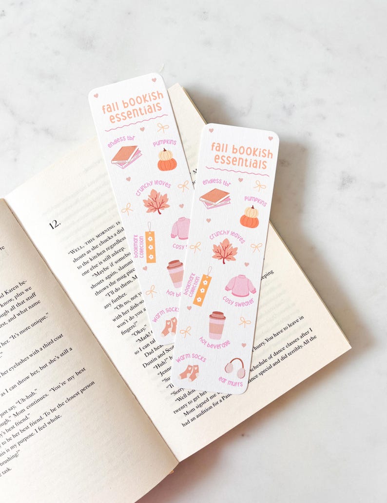 K&ouml;nnte beinhalten: Zwei rechteckige Lesezeichen mit dem Text "fall bookish essentials" und herbstlichen Illustrationen. Die Lesezeichen zeigen Bilder von K&uuml;rbissen, Bl&auml;ttern, B&uuml;chern und Kaffeetassen.