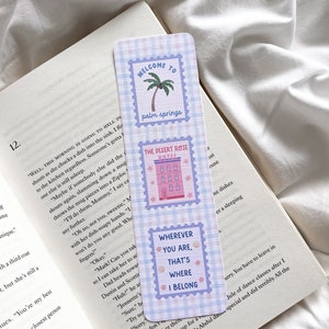 May include: A rectangular bookmark with a blue and white checkered pattern. The bookmark features three postage stamp-style designs with text: "WELCOME TO palm springs", "THE DESERT ROSE HOTEL", and "WHEREVER YOU ARE, THAT'S WHERE I BELONG".