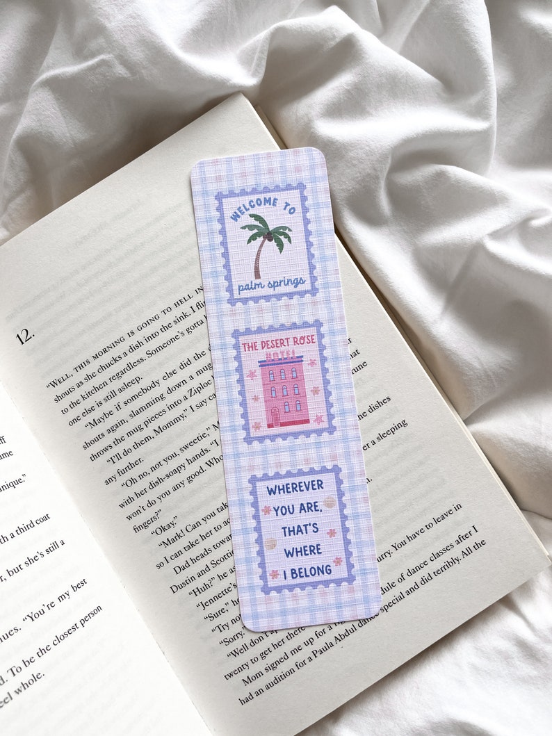 May include: A rectangular bookmark with a blue and white checkered pattern. The bookmark features three postage stamp-style designs with text: "WELCOME TO palm springs", "THE DESERT ROSE HOTEL", and "WHEREVER YOU ARE, THAT'S WHERE I BELONG".
