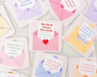 May include: A collection of square cards with envelope designs, each containing a reading prompt. The cards are in various pastel colors, with text such as "Your Next Read is a Magical Realism Novel." The central card reads "the book lovers tbr cards."