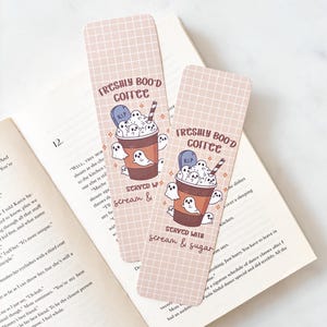 May include: Two Halloween-themed bookmarks with a grid pattern. Each bookmark features a coffee cup with ghost illustrations and the text "FRESHLY BOO'D COFFEE" and "SERVED WITH scream & sugar".