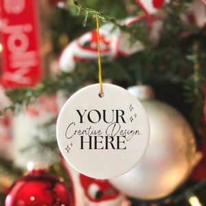May include: White round Christmas ornament with black text that reads "Your Creative Design Here" with a gold string hanging from the top.