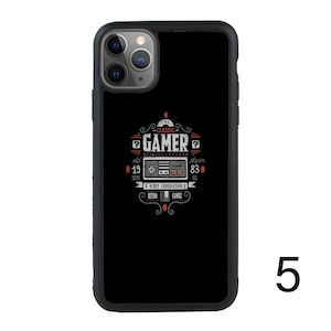 Puede incluir: Carcasa de tel&eacute;fono negra con un dise&ntilde;o de juego retro. El dise&ntilde;o presenta un mando de videojuego vintage con el texto "The Classic Gamer" y "8-Bit Generation of Retro Games".