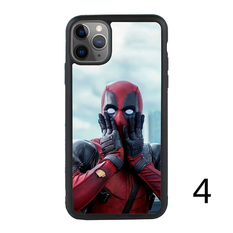 May include: A black phone case with a red and black Deadpool character image. The character is covering their face with their hands. The case has a black border and a clear background.