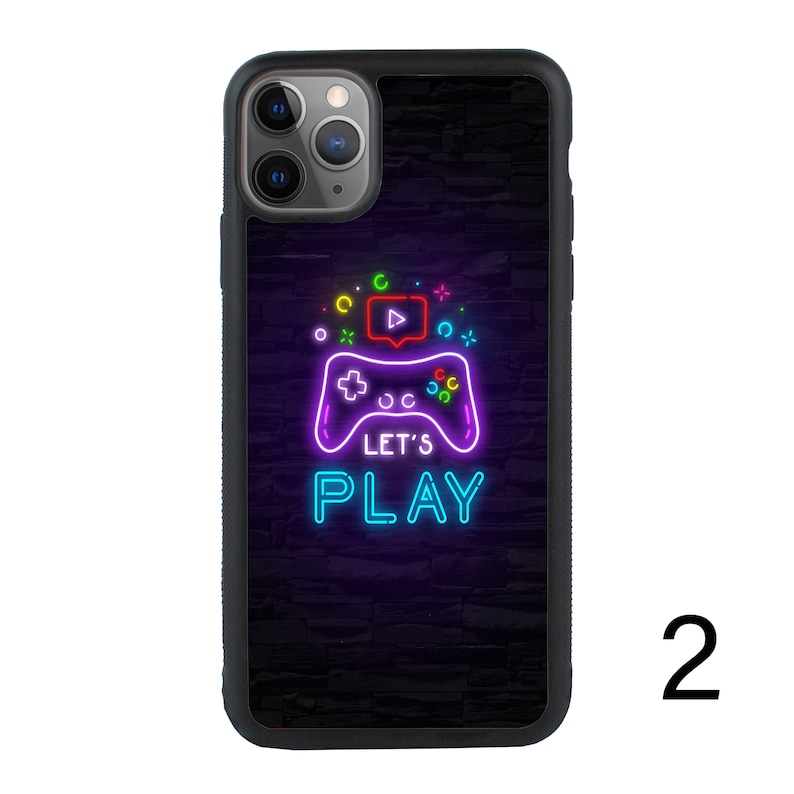 Puede incluir: Carcasa de tel&eacute;fono negra con un gr&aacute;fico de mando de videojuego verde ne&oacute;n, azul y rosa y el texto "Let's Play".