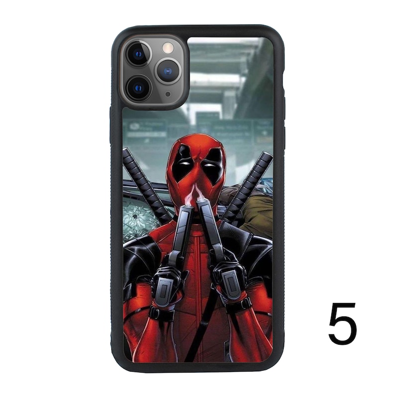 May include: Black phone case with a graphic of Deadpool holding two guns in front of his face. The background is a blurry image of a city street.
