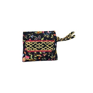 May include: A quilted fabric wallet featuring a black base with a colorful floral pattern. The front flap displays a prominent yellow geometric lattice design bordered by red trim. A matching fabric wrist strap is attached to the side of the wallet.