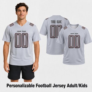 May include: A light gray V-neck football jersey featuring the text YOUR TEAM and the number 00 in dark gray with a maroon outline on the front. The back displays the text YOUR NAME above the number 00 in the same dark gray and maroon color scheme.